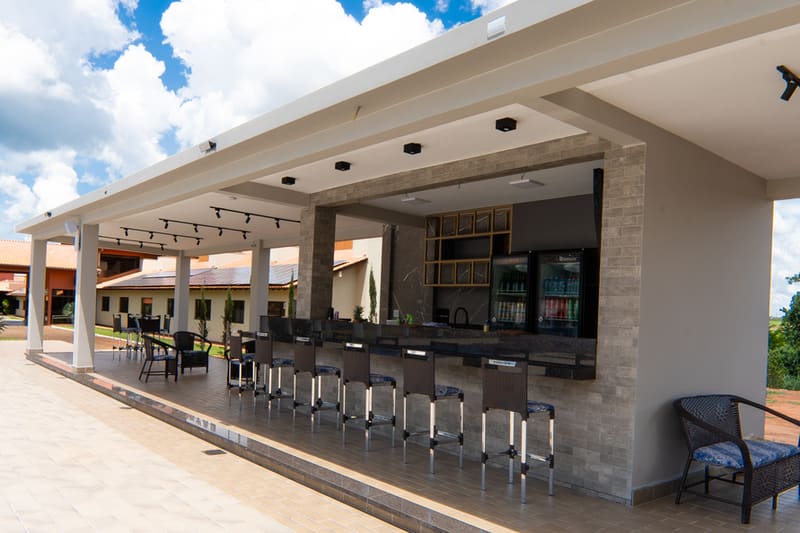 Bar da piscina coberto, com bancos e geladeira de bebidas