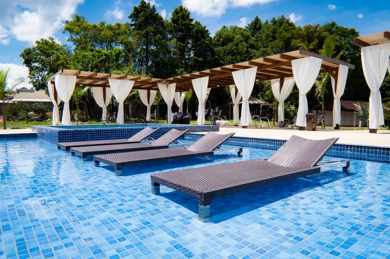 Piscinas externas com espreguiçadeiras submersas e gazebos