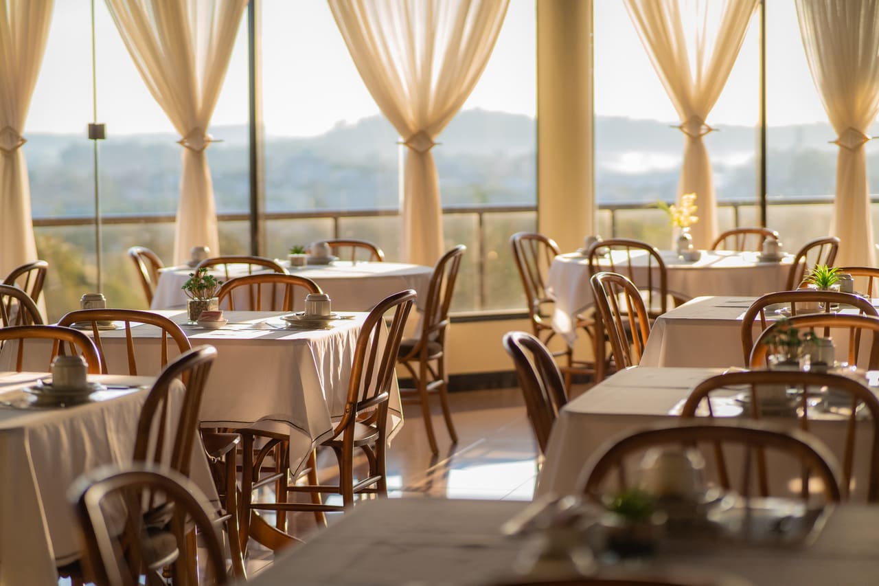 Restaurante ao entardecer com mesas postas e luz natural